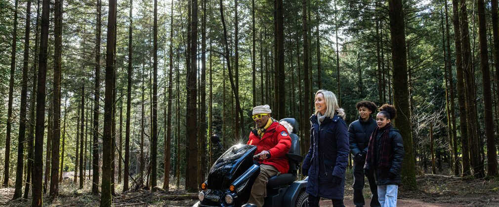 Family with mobility scooter in a pine forest