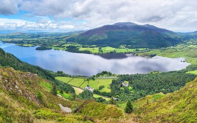 A view across a lake to a forested mountain in the background