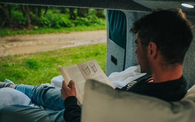 A man reading a book in a campervan