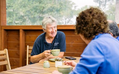 Three people enjoying some hot drinks on a wooden table in an outdoor cafe