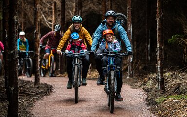 Family with small children on bikes in a forest