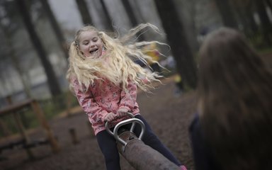 girl playing on a see-saw in the forest