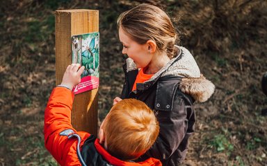 Two children looking at a gruffalo orienteering marker post