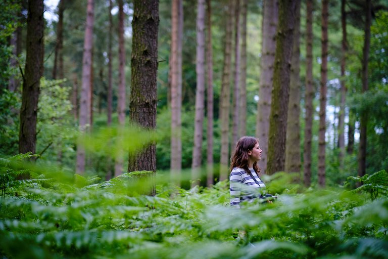 Woman stood amongst large leaves in the forest
