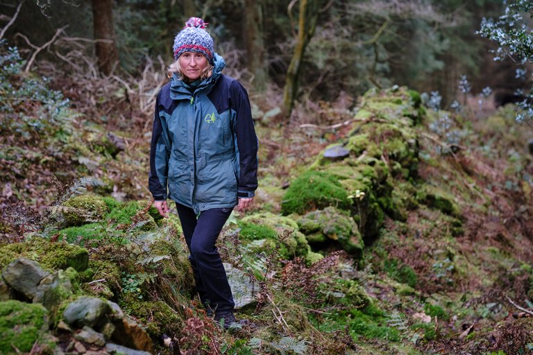 Woman stood on mossy rocks in the rich forest
