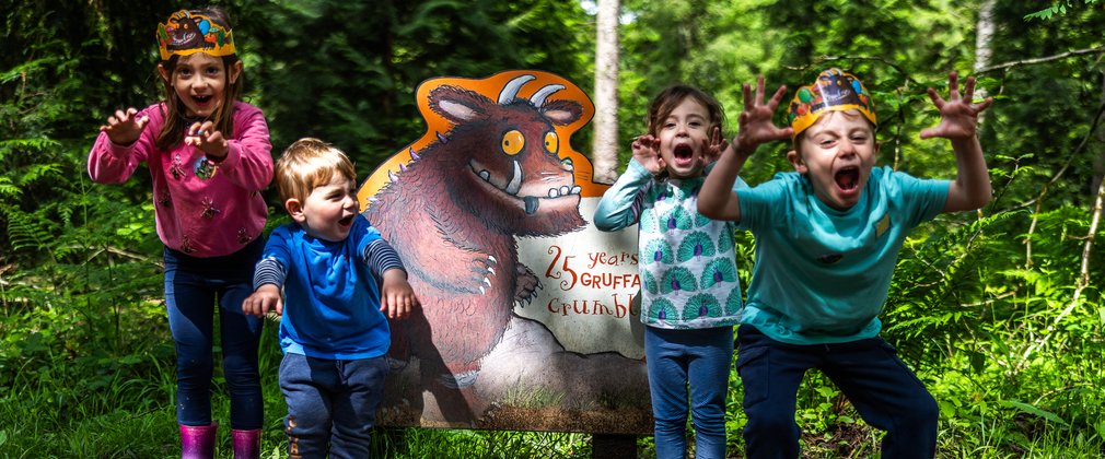 Group of children pulling faces in front of a Gruffalo sign