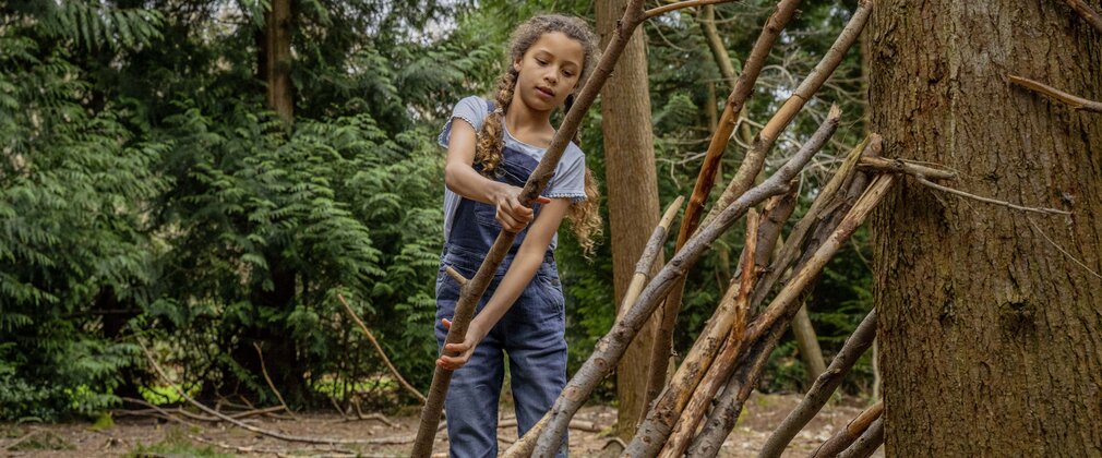 Child building a den out of sticks in the forest