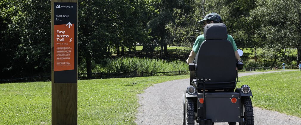 A person sitting on an all-terrain mobility scooter on the Easy Access Trail at Alice Holt Forest