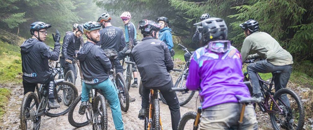 A group of cyclists stopped on a wet forest trail