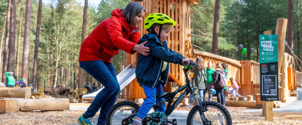 Child cycling with help of mother at Pedal and Play