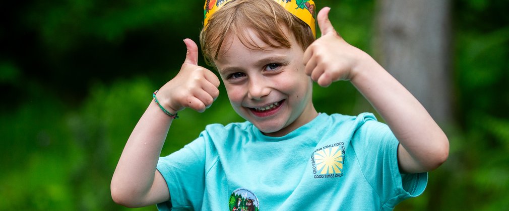 Young boy wearing Gruffalo crown, with his thumbs up