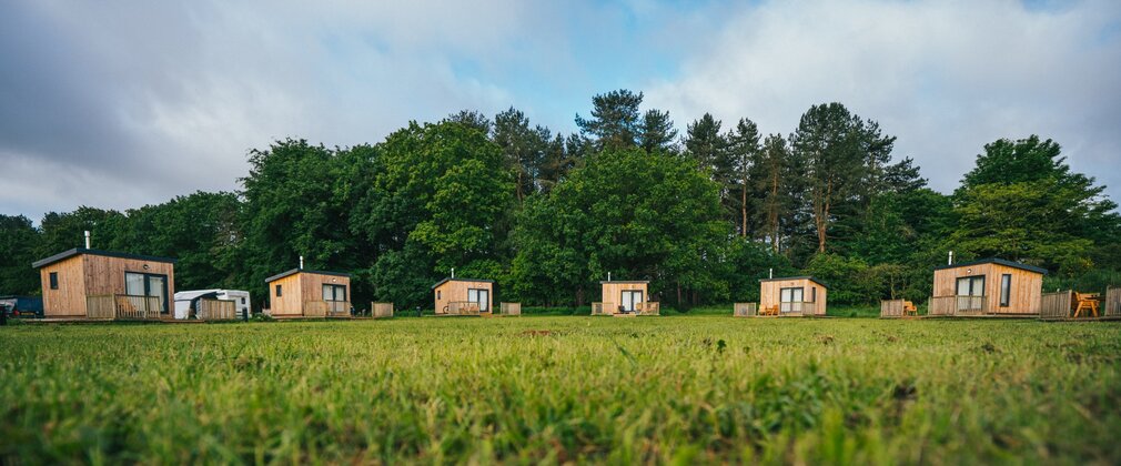 Row of woodeng glamping pods on a campsite