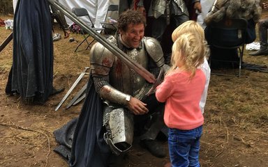 Actor dressed in knights armour talking to children