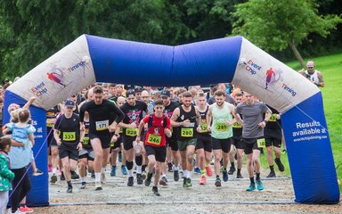 A large group of runners standing behind an inflatable arch