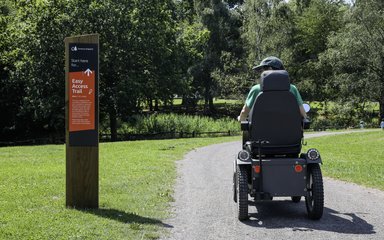 A person sitting on an all-terrain mobility scooter on the Easy Access Trail at Alice Holt Forest