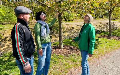 A woman wearing Forestry England uniform pictured outside on a forest path with two visitors.