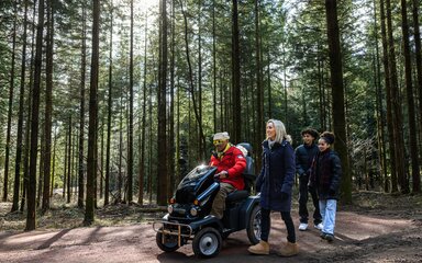 Family with mobility scooter in a pine forest