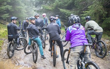 A group of cyclists stopped on a wet forest trail