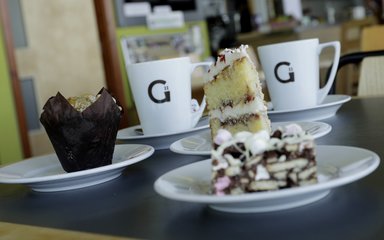 A piece of cake and some cups with the Grounds logo on them