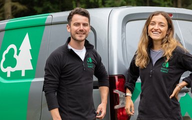 Group of Forestry England staff stood smiling in front of grey Forestry England van