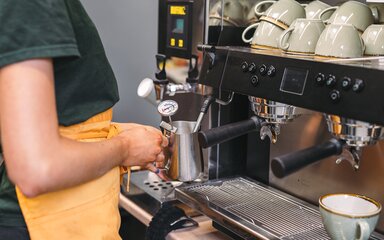A person frothing milk at a coffee machine
