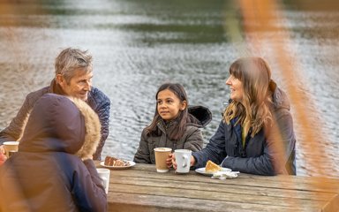A family sitting next to a lake enjoying tea and cake at Bedgebury Cafe 
