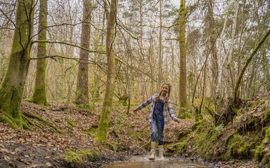 Girl walking through muddy puddle in the forest