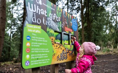 Young girl playing with an interactive sign lifting a panel