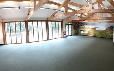 Inside a meeting room. Beams are on display and there is full length windows. The room is empty.