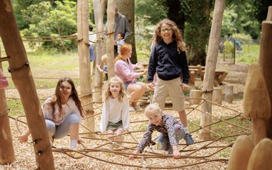 Kids play in the playground on a spider web rope feature. 