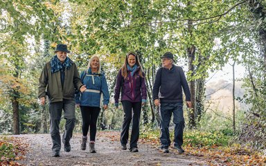 Group of four smiling people walking in an autumnal wood 