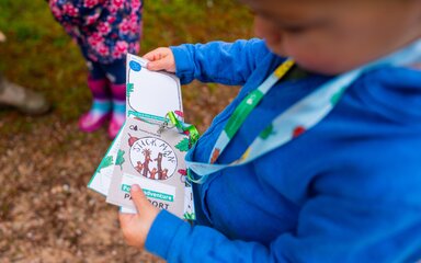 Child in blue jumper examining a lanyard with Stick Man branded cards.