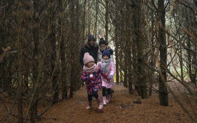 Family running through lines of bare trees in winter