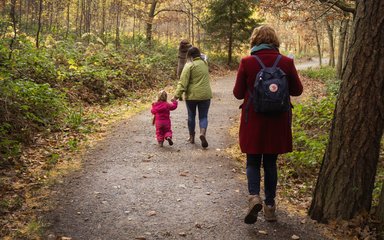 Mother and child walking on forest path during autumn