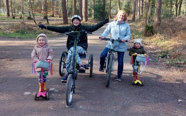 Family with an adapted bike cycling through the forests