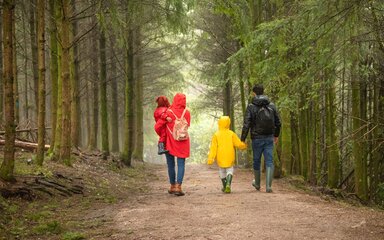 Two adults and two children walking on a forest path in winter.