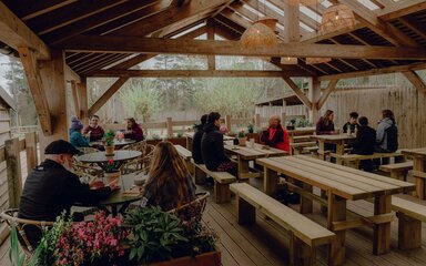 Diners seated in a wooden decking area decorated with plants
