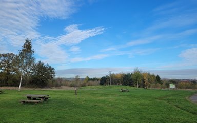 Picnic benches on a grassy area under bright blue skies