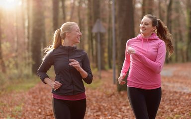 adults on a run on a woodland trail with autumn leaves