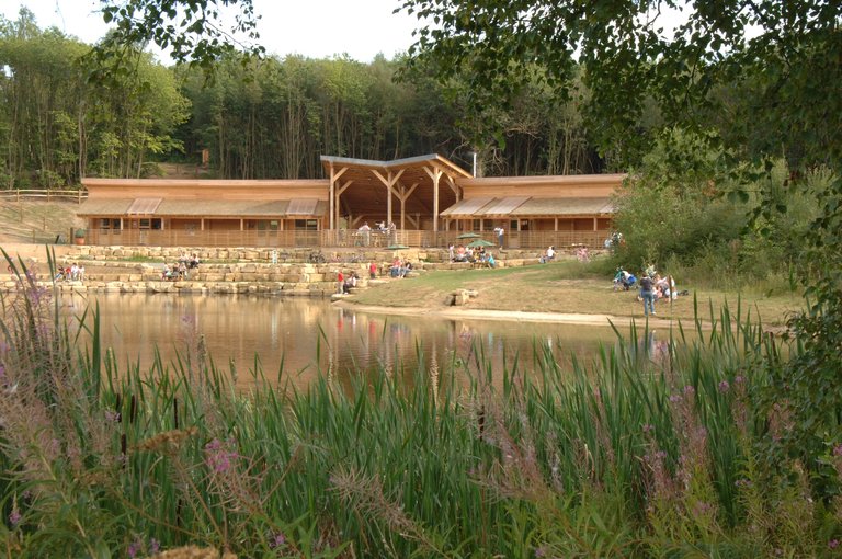 A large wooden visitor centre shown across a pond