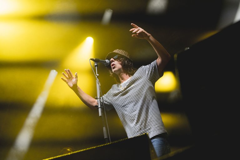 Close-up of male singer Richard Ashcroft on stage, wearing a striped t-shirt and bucket hat.