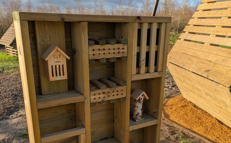 A multi-level wooden bug hotel in a playground