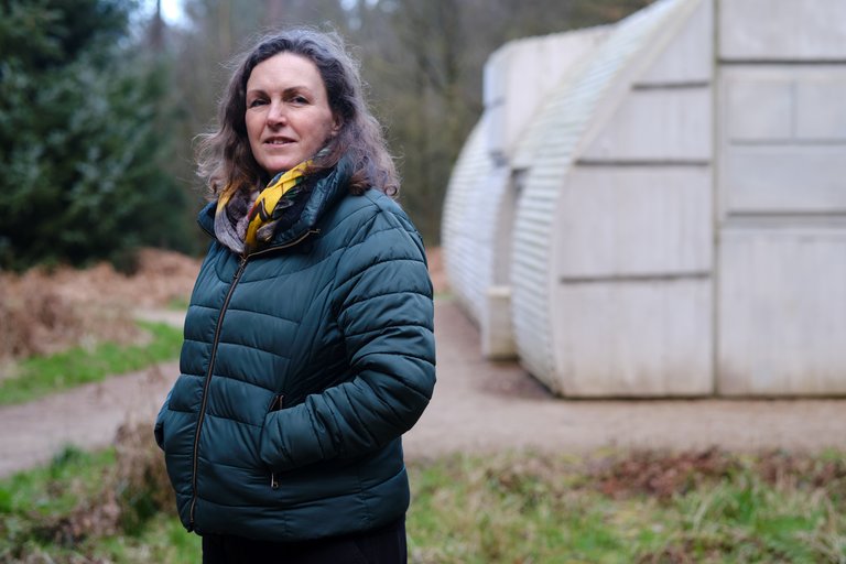 Woman stood in front of concrete artwork in the forest